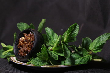 bowl with tobacco for hookah. fruits on a black background. smoking hookah