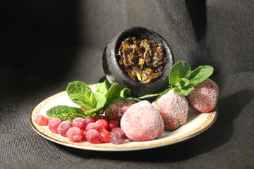 bowl with tobacco for hookah. berries on a black background