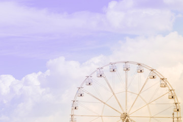 Ferris wheel on the colorful cloudy sky. Background concept of happy holidays time.