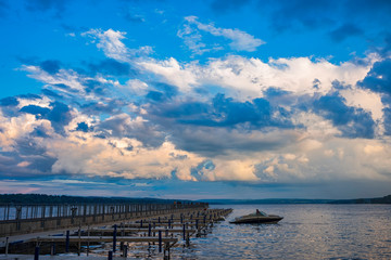 A motorboat docks at the public boat dock and pier in Skaneateles Lake, Skaneateles, in the Fingerlakes Region of New York State around the time of a summer sunset in August .