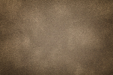 Background of light bronze suede fabric closeup. Velvet matt texture of brown nubuck textile