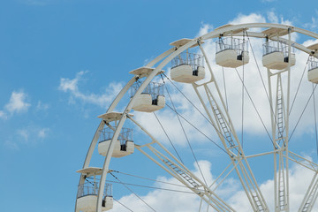 Obraz premium Ferris wheel on the blue cloudy sky. Background concept of happy holidays time.