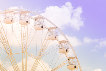 Ferris wheel on the colorful cloudy sky. Background concept of happy holidays time.