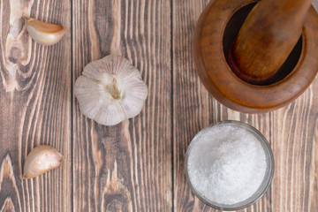 garlic, salt and wooden mortar on a wooden background