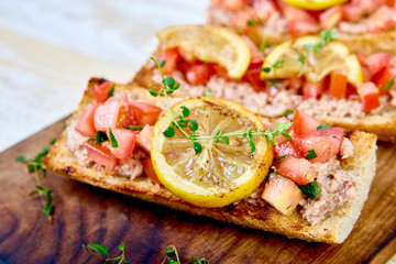 Appetizer bruschetta with tuna and tomatoes. Italian cuisine. Delicious Italian antipasti crostini on wooden board. Copy space.