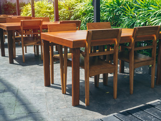 Wooden dining table set near the green garden.