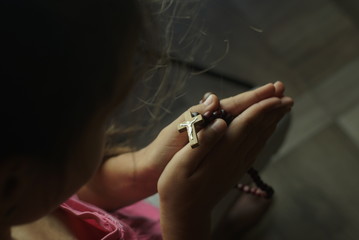 young girl prays with wooden rosary