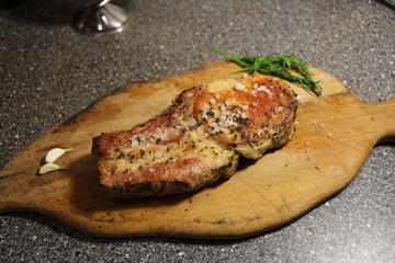 fried pork steak on the bone on a wooden board.