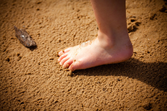 Baby on the beach. Children's foot on the summer beach