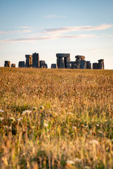 Sunrise at Stonehenge with golden wheat fields and clouds lit by warm sunlight northern England, UK
