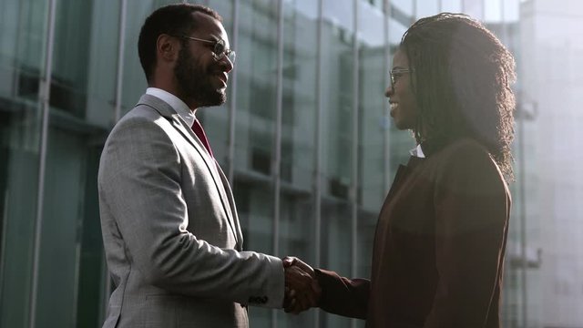 Two young people shaking hands outdoor. Closeup shot of two employees shaking hands and gesticulating. Business handshake concept