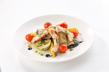 grilled octopus with zucchini, tomato and eggplant on white plate isolated on white background