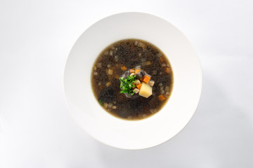 Thick forest mushroom soup with potatoes on white plate isolated on white background