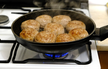 Pork cutlets are fried in a pan on a gas stove.