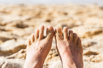Woman feet on sand beach. Closeup barefoot woman legs relaxing near sea. Travel and vacation concept.