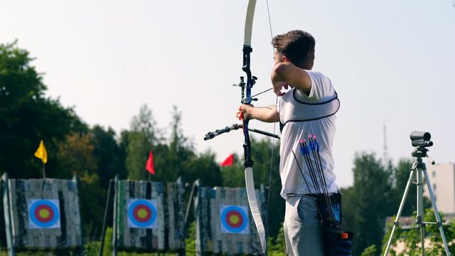 Male athlete aiming at target with a bow.
