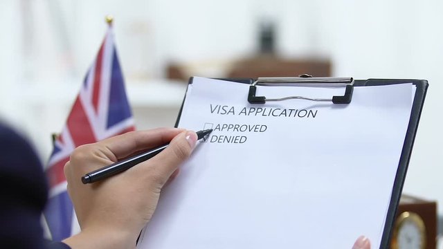 Female embassy worker checking United Kingdom visa application, marking denied