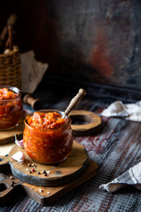 two glass jars with home made red vegetable caviar, ratatouille, ragout on wooden brown boards