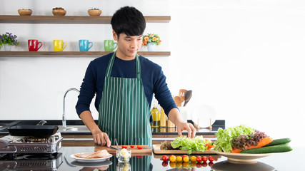 Asian happy man preparing to cooking vegetable salad with smiling in the modern home kitchen. Healthy food concept