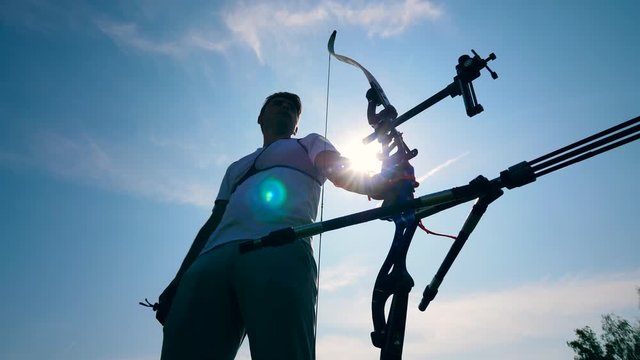 Athlete stands with a bow in hands.