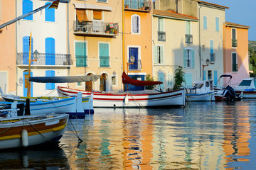 Fototapeta na wymiar facade of mediterranean building with colorful shutter with river and boat