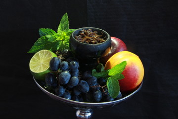 bowl with tobacco for hookah. berries on a black background