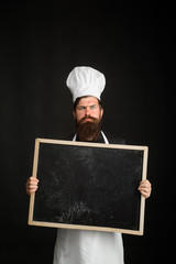 Man chef holds blank board for text advertising. Copy space for restaurant advertising. Healthy menu. Diet. Handsome cook holds blank chalkboard. Food service. Cuisine. Culinary. Healthy food cooking.