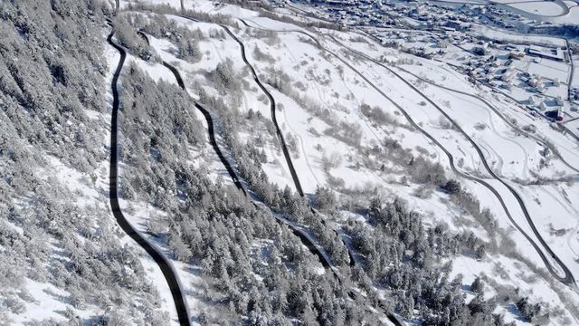 4K Winter holidays mountain road in a snowy white landscape. Cinematic drone shot to discover the scenic view with a white valley in the background