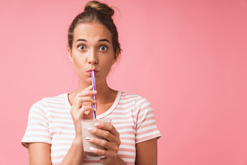 Image closeup of surprised young woman expressing wonder and drinking chocolate milk with straw