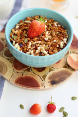 granola with strawberries in a plate on a white table