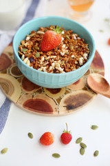 granola with strawberries in a plate on a white table