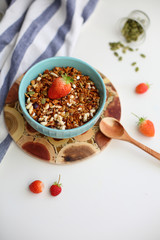 granola with strawberries in a plate on a white table