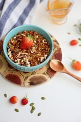 granola with strawberries in a plate on a white table