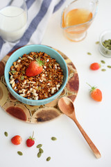 granola with strawberries in a plate on a white table
