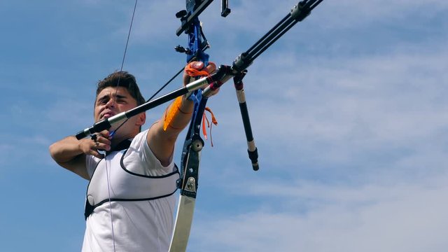 A man aims at a target and shoots a bow.