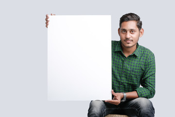 young indian guy holding blank poster