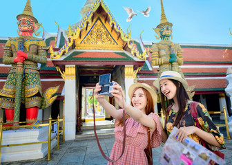 Obraz na płótnie Canvas young tourist women enjoy taking selgie picture in the palace temple in Bangkok of Thailand Emerald Buddha Temple, Wat Phra Kaew, Bangkok Royal Palace popular tourist place