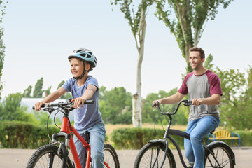 Fototapeta na wymiar Happy father and son riding bicycles outdoors