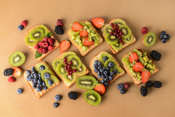 Tasty sandwiches with kiwi and berries on color background