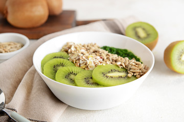 Bowl with tasty oat flakes and kiwi on white table