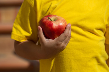 Child with red apple and yellow t-shirt