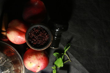 bowl with tobacco for hookah. fruits on a black background. smoke hookah