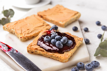 Toasted bread with sweet jam and peanut butter on white board