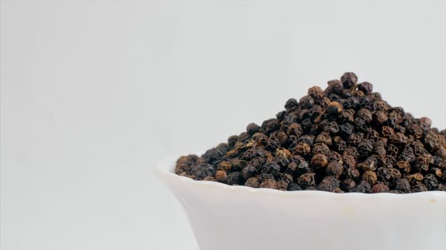Pan shot of a rotating bowl filled with black pepper (Kaali Mirch - Indian Spice). 