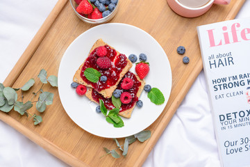 Plate with toasted bread, tasty jam and berries on tray