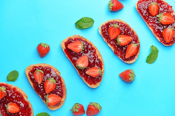 Toasted bread with tasty strawberry jam on color background