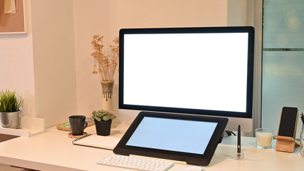 Mockup tablet and computer on creative workspace with warm light.
