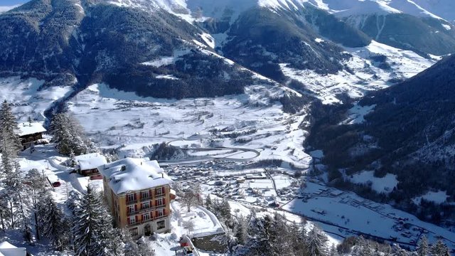 4K Switzerland winter wonderland cinematic aerial shot. Drone flying over a hotel with scenic valley in the background