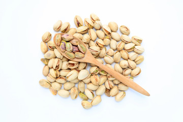 Pistachio nuts isolated on white background with wooden spoon. Top view.