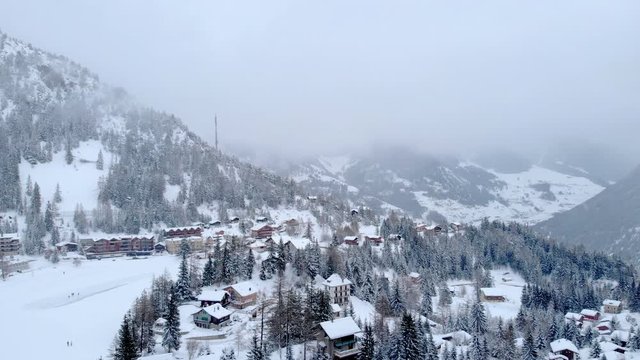 Alpine village on a cold winter day aerial shot. Snow and fog in a frozen landscape